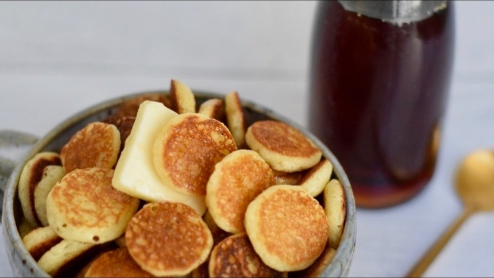 Cereal pancakes with syrup and butter in blue ceramic bowl