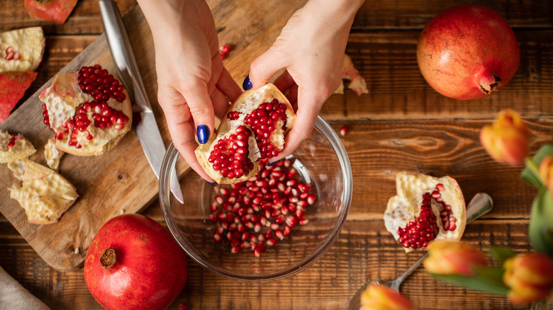 hands shucking pomegranates