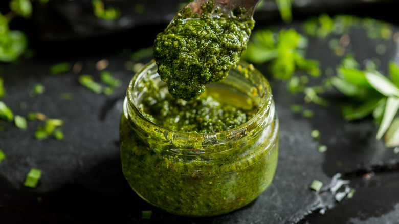 Spoon getting pesto from jar