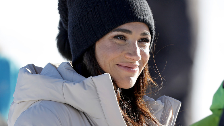 Meghan Markle smiling in black hat