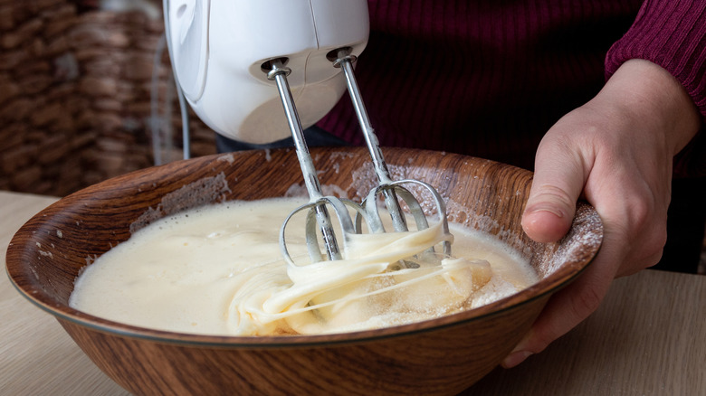 Person using electric hand mixer