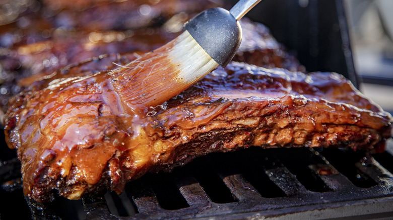 Brushing saucy ribs on grill