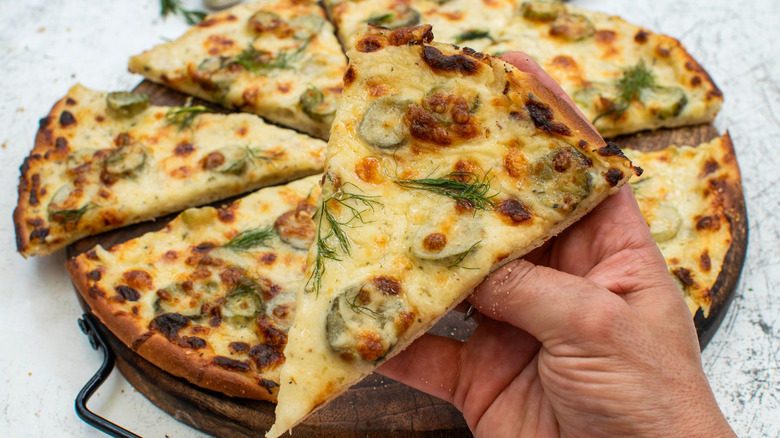 dill pickle pizza slice with hand