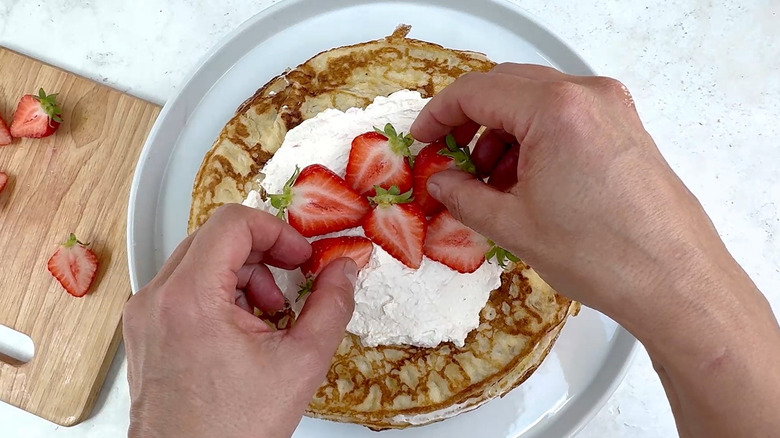 decorating strawberries and cream crepe cake