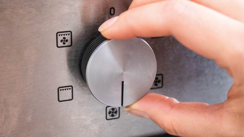 hand turning dial on oven